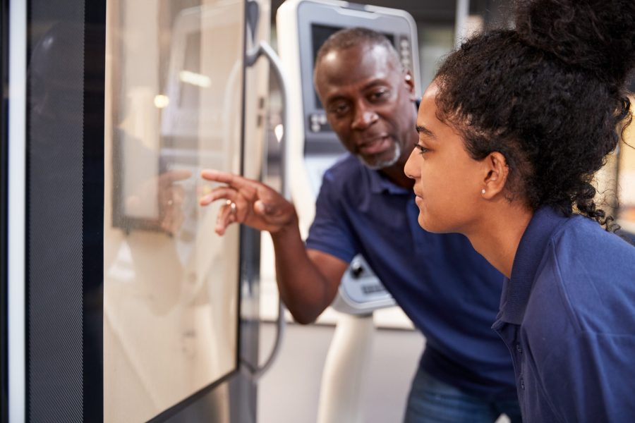 Engineer showing apprentice how to use a tool-making machine